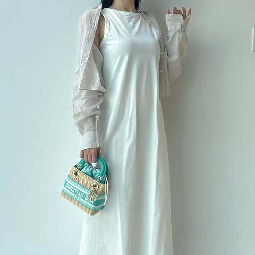 ディオールのかごバッグを持つ白いワンピースの女性