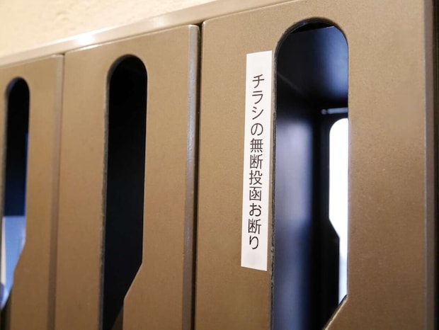 「チラシの無断投函お断り」ステッカーが貼られた集合郵便受けのアップ