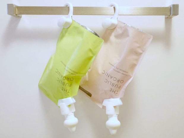 詰め替えパウチにポンプをつけて浴室バーに吊り下げた黄緑とピンクの2本