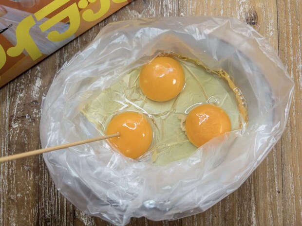 アイラップに割り入れた卵3個の卵黄に竹串で穴を開けている俯瞰写真