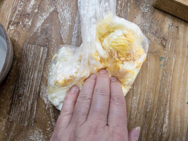 加熱後のアイラップを袋の外から手で揉んで卵をスクランブル状に砕いている工程写真