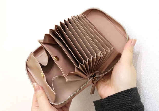 ピンクのやみつきサイフを両手で開いてじゃばら仕様の内部を見せている様子