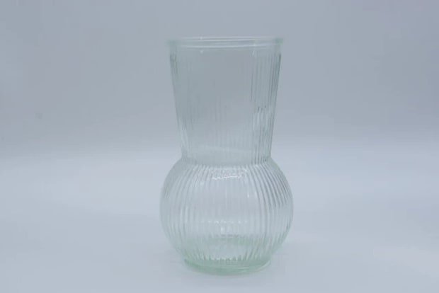 縦リブ模様の透明なガラスフラワーベースが白い背景に置かれている