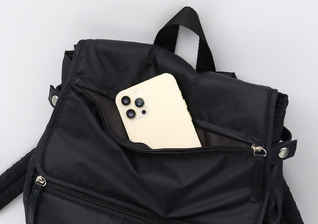 フラップ部分のポケットからスマートフォンを取り出している様子