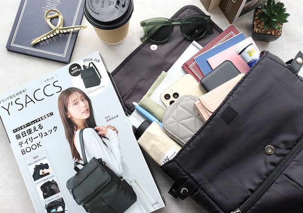 ムック本と荷物を入れたリュックを小物と並べて俯瞰で撮影した写真