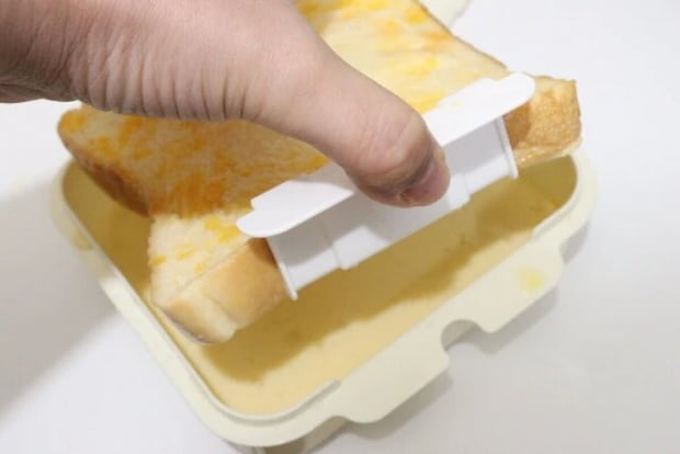 ダイソーのフレンチトーストメーカーのバスケットを使って卵液をしみ込ませたパンを引き上げる