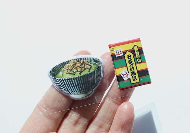 お茶碗とお茶づけ海苔小袋モチーフのぷっくりシール2点を手のひらに乗せた様子