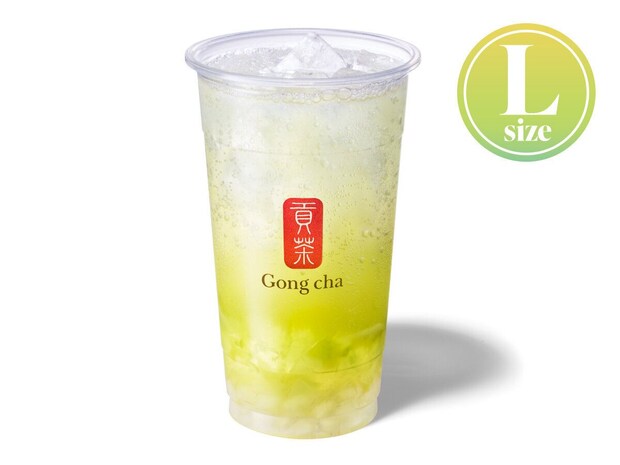 ゴンチャ SHINE シャインマスカット スパークリングティーの商品写真 ゴンチャの透明Lサイズカップに入った「SHINE シャインマスカット スパークリングティー」。炭酸の泡が見える黄緑色の飲料に氷とシャインマスカットゼリーが入っている