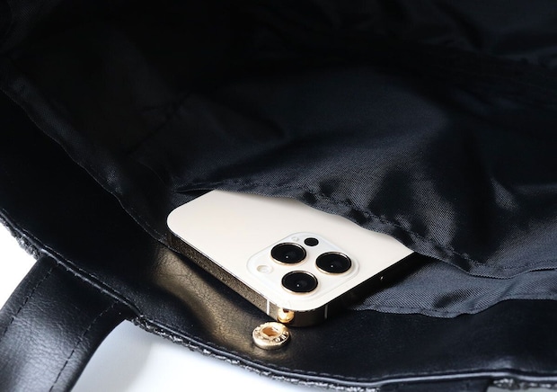 黒いラフィア風かごバッグの黒い裏地の内ポケットに白いゴールドフレームのスマホを斜めに収納したアップ写真