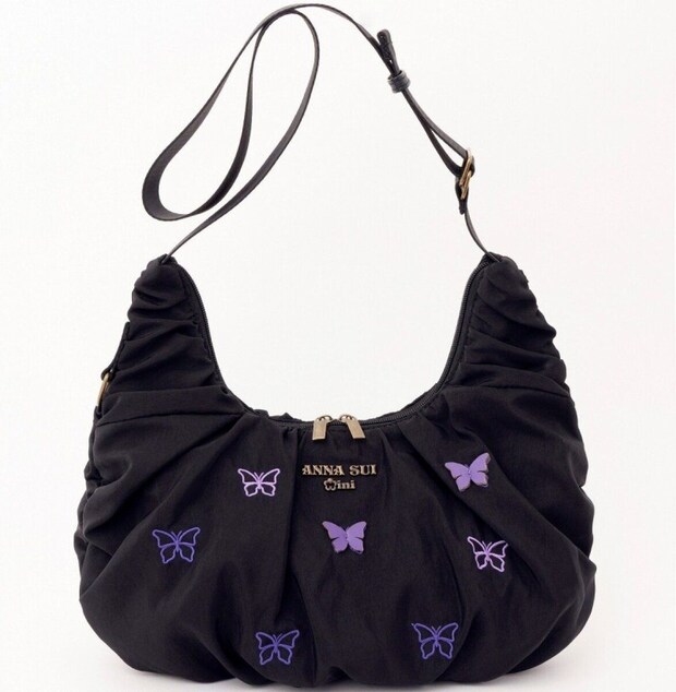 ANNA SUI miniの黒いクロワッサンバッグをショルダーストラップを長く伸ばして斜め掛けできる状態にしたもの。パープルの蝶の刺繍と立体パーツが全面にあしらわれている