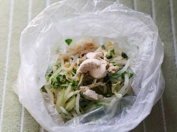 水分を絞ったもやしと豆苗の入ったビニール袋に、白い顆粒状の中華スープの素などの調味料を加えたところ