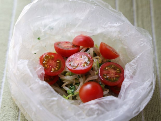 和えたもやしと豆苗に、半分に切った赤いプチトマトを加えた透明なビニール袋の中身