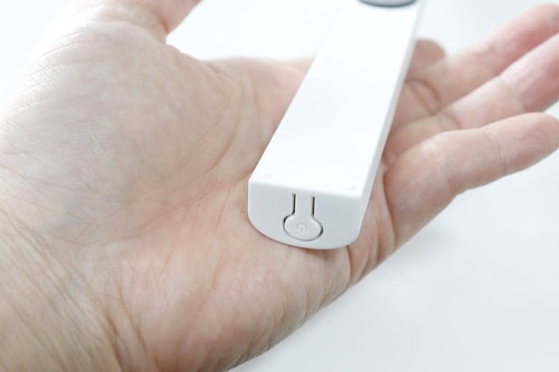 本体端にある電源スイッチのアップ 手のひらに乗せた本体の端のアップ。電源マークが刻印された電源スイッチが見える