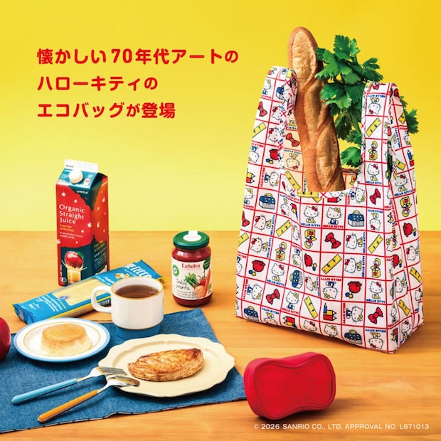 黄色い背景の食卓に置かれた、赤い格子柄に70年代風ハローキティのイラストが並ぶエコバッグ。バゲットや野菜が入り、手前に赤いリボン型ポーチも