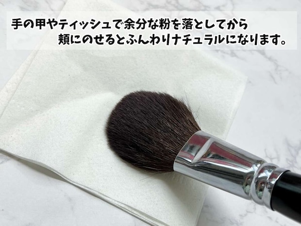 ティッシュの上でチークブラシの余分な粉を落とすようす