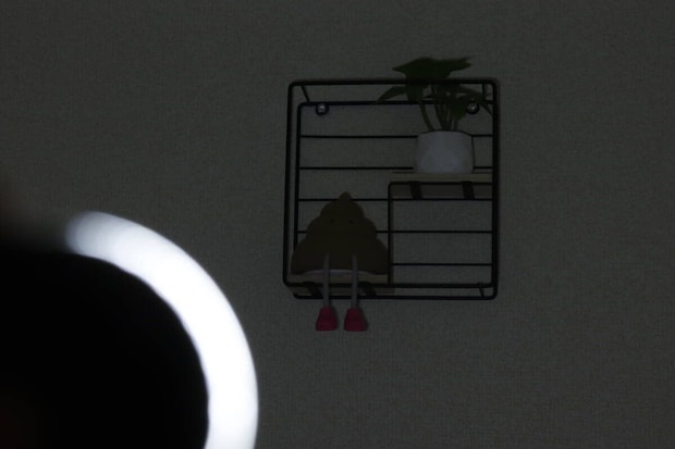 暗い部屋でライトのCOBモードLowを壁の棚に当てて薄暗く照らしている