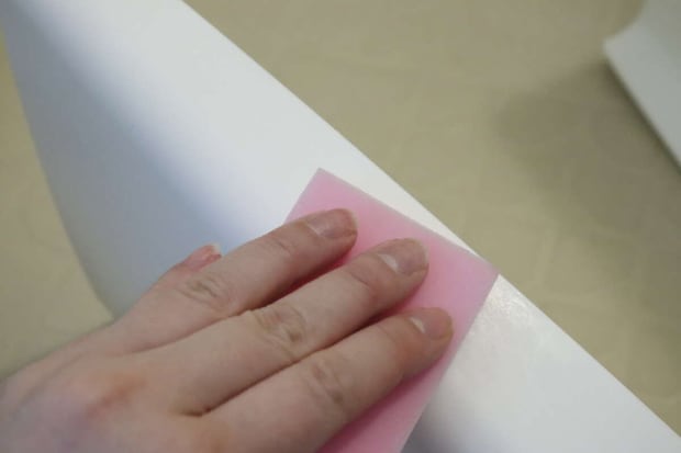 ピンクのメラミンスポンジでお風呂の椅子を掃除する手 ピンクのメラミンスポンジでお風呂の椅子を掃除する手