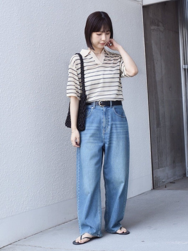 ボーダー柄スキッパーニットとワイドデニムを着用し立つ女性