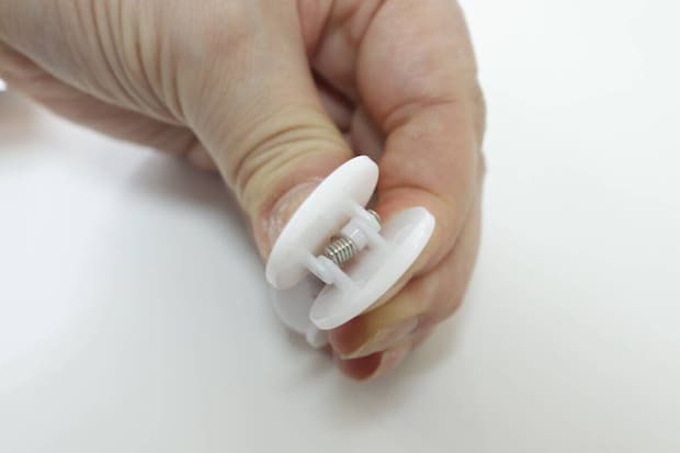 指で白いクリップを開き、内部のバネが見えている 指で白いクリップを開き、内部のバネが見えている