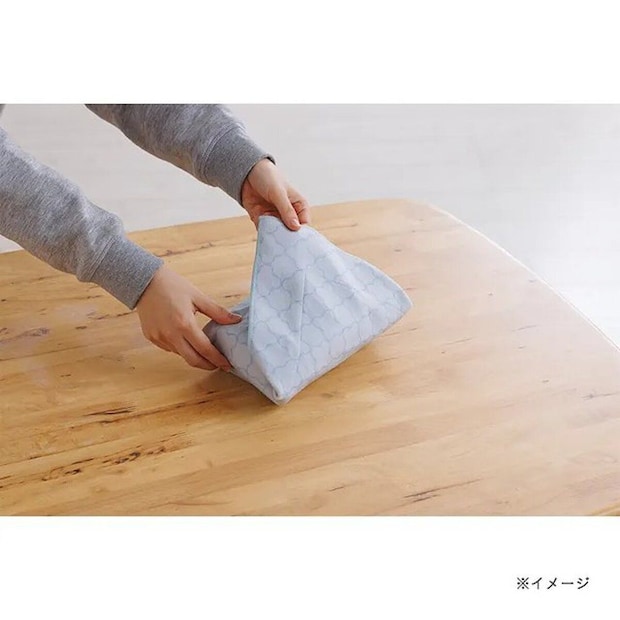 木目のテーブルで水色の保冷マルチクロスをたたむ手元。