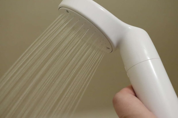 浴室で白いシャワーヘッドから水が出ている様子