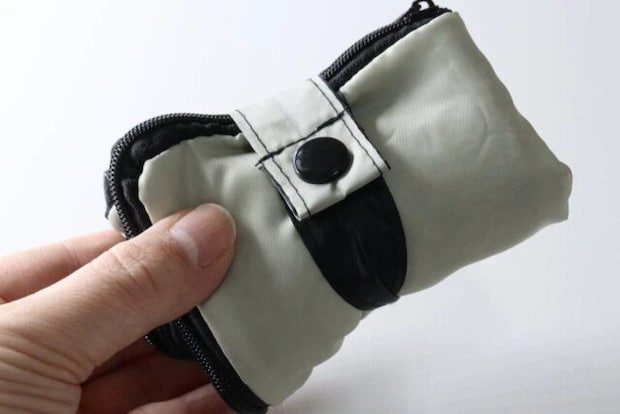 コンパクトに折り畳まれた傘カバーを片手で持っている
