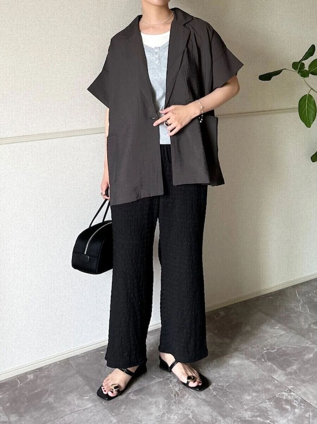 黒いシャーリングパンツと半袖ジャケットを着た女性