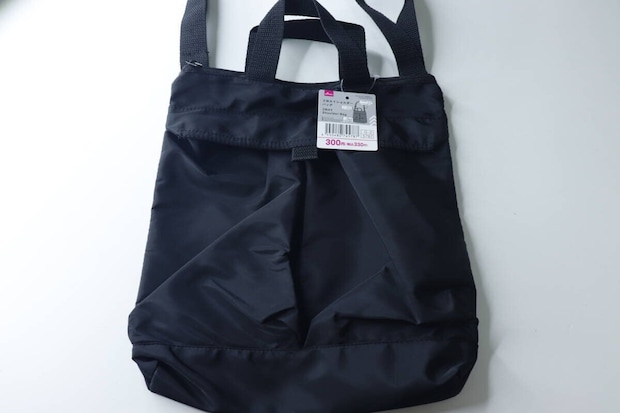 黒い2WAYショルダーバッグが白い背景に置かれ、商品タグが付いている状態