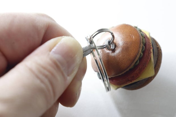 ハンバーガー型キーホルダーのダブルリングにオープナーを差し込む手元