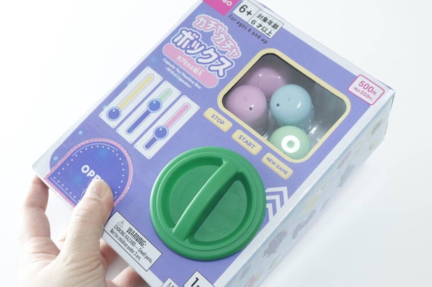 女性がダイソーのガチャガチャボックスを手に持っている