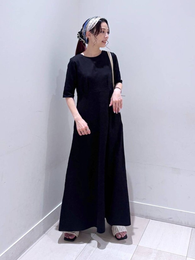 黒いフレアワンピースを着た女性、頭にスカーフを巻いて横向き