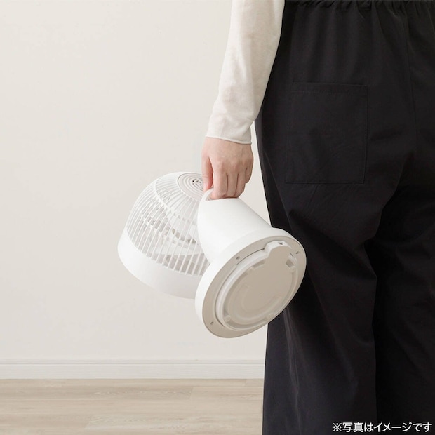 黒いパンツの人が白いサーキュレーターを片手で持っている