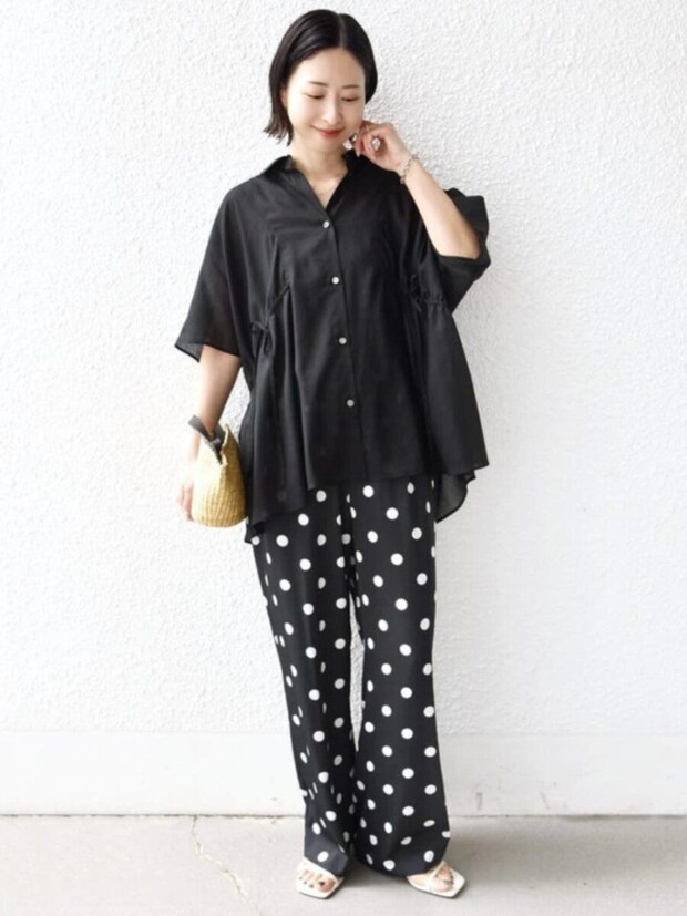 黒いシアーシャツとドット柄パンツを着てカゴバッグを持つ女性 黒いシアーシャツとドット柄パンツを着てカゴバッグを持つ女性