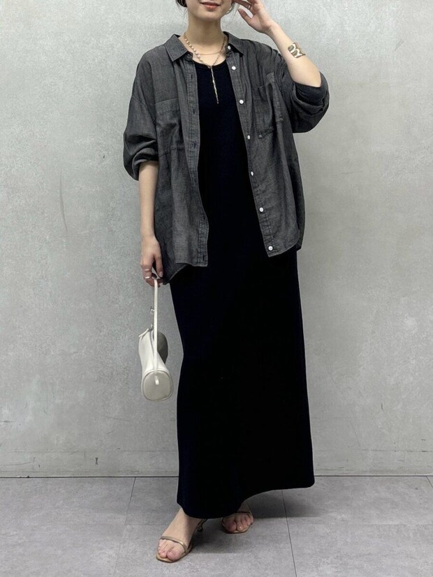 黒いワンピースにデニムシャツを羽織り白いバッグを持つ女性 黒いワンピースにデニムシャツを羽織り白いバッグを持つ女性