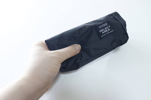 黒いショルダーバッグをコンパクトに折りたたみ片手で持つ 黒いショルダーバッグをコンパクトに折りたたみ片手で持つ