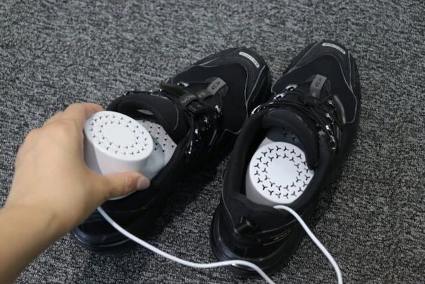 黒いスニーカーにシューズドライヤーを差し込む手元