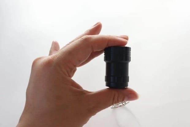 黒い筒状のLEDライトを指でつまんで見せている手元