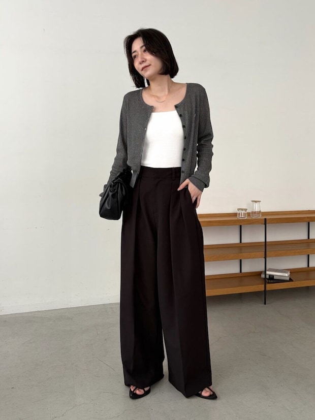 ショートヘアの女性がグレーカーデと黒ワイドパンツを着る ショートヘアの女性がグレーカーデと黒ワイドパンツを着る