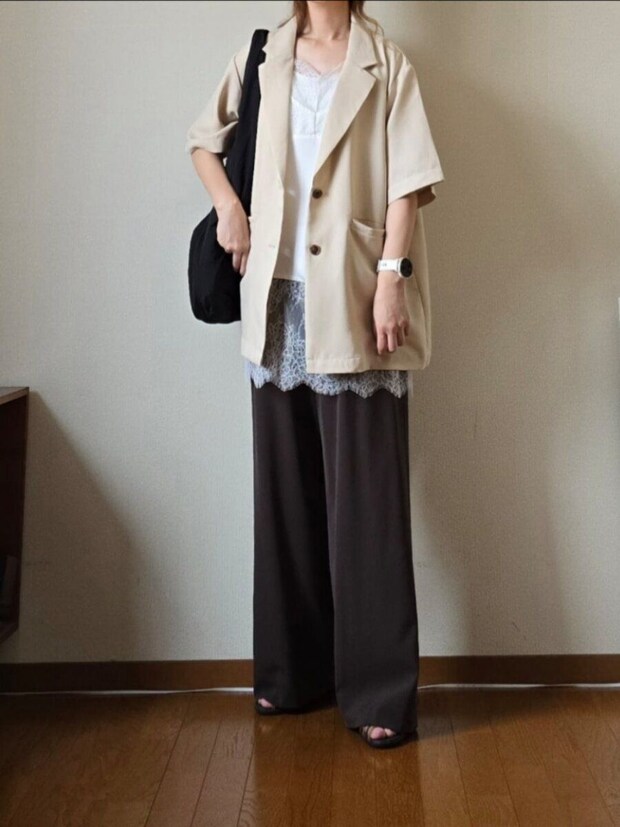 ベージュの半袖ジャケットとモカ色ワイドパンツ、レースキャミソールを着た女性。 ベージュの半袖ジャケットとモカ色ワイドパンツ、レースキャミソールを着た女性。