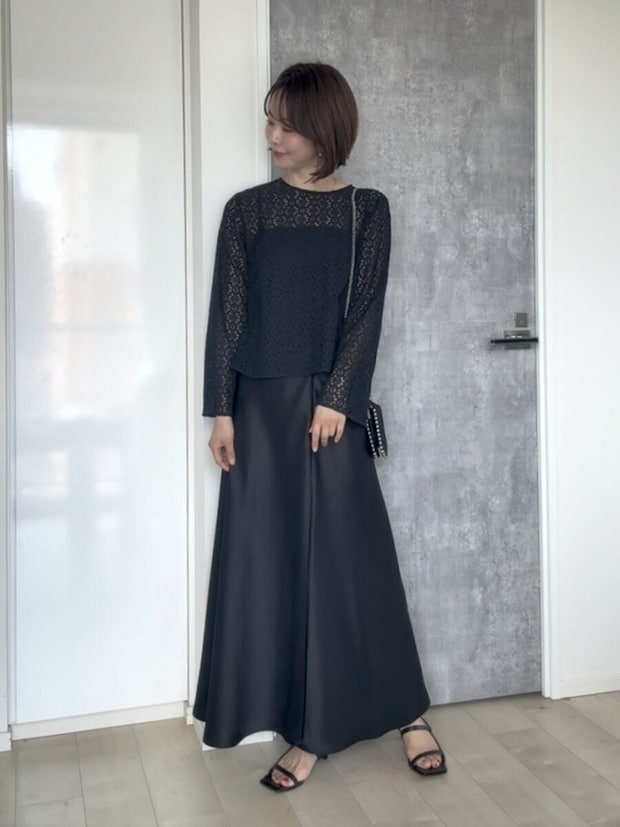 黒いレースブラウスと黒いスカートのワントーンコーデの女性
