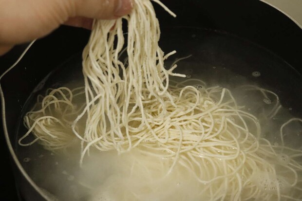沸騰したお湯の中で白く茹でられている生そうめん