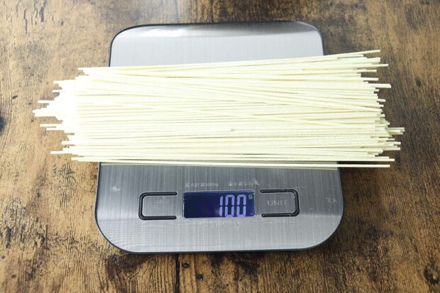 デジタルスケールの上に棒ラーメンの麺が100g計量されている様子