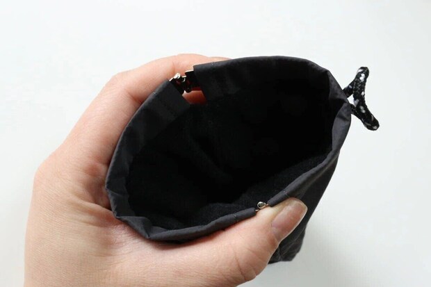 手で開かれたグレーのバネ口ポーチの開口部 手で開かれたグレーのバネ口ポーチの開口部