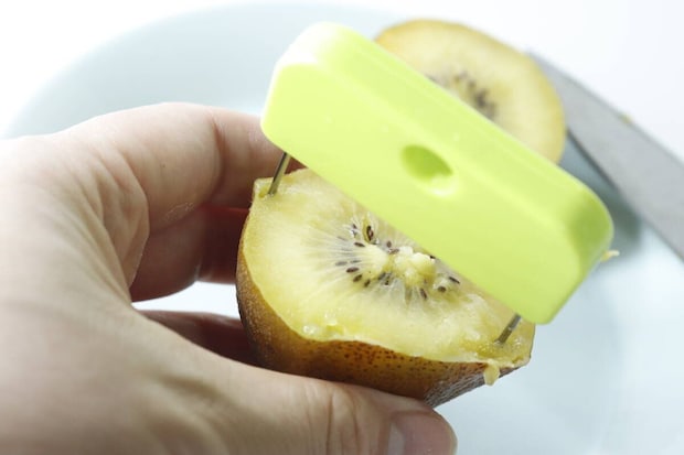 キウイの断面に皮むき器の細い針が刺さっている手元 キウイの断面に皮むき器の細い針が刺さっている手元