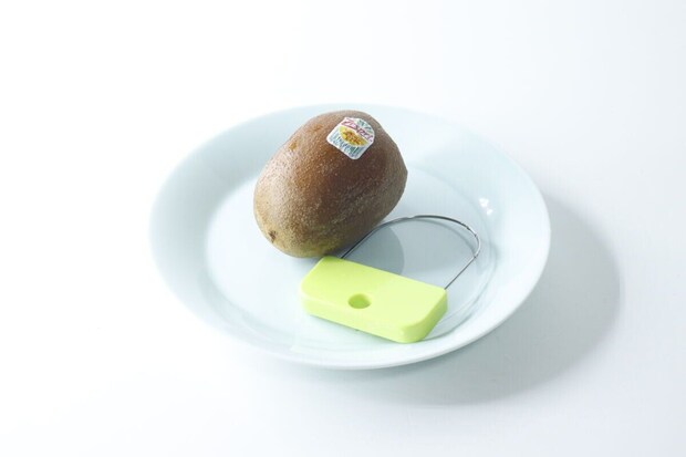 白い皿にキウイと緑色の皮むき器が置かれている 白い皿にキウイと緑色の皮むき器が置かれている