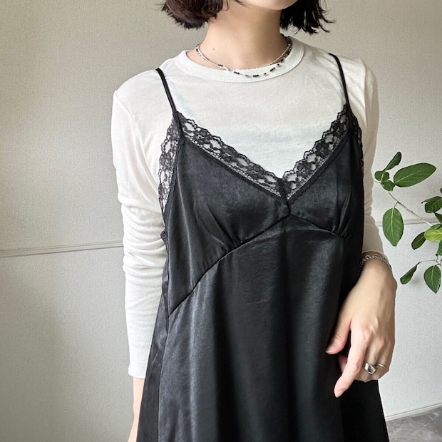 白いロンTと黒いサテンキャミソールを重ね着した女性の胸元アップ