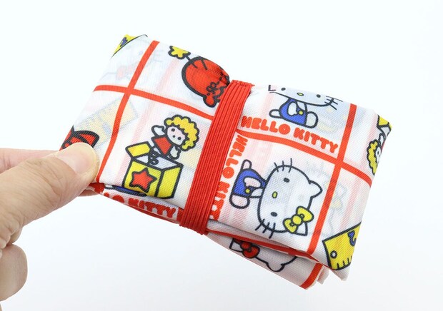 赤いゴムでコンパクトにたたまれたエコバッグを持つ手