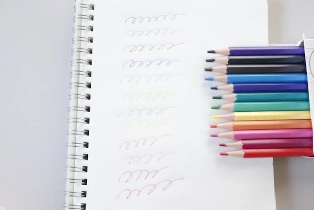 ノートに色鉛筆で波線が描かれ、色鉛筆の箱が横に置かれている