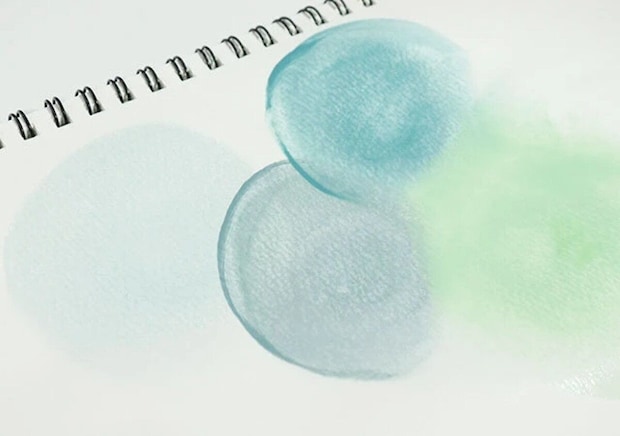 ノートに水彩絵の具でくすみカラーの丸やグラデーションが描かれている