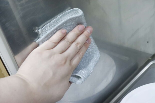手が「凄腕くんお助けクロス」のループ繊維面でステンレス壁面を拭いている 手が「凄腕くんお助けクロス」のループ繊維面でステンレス壁面を拭いている